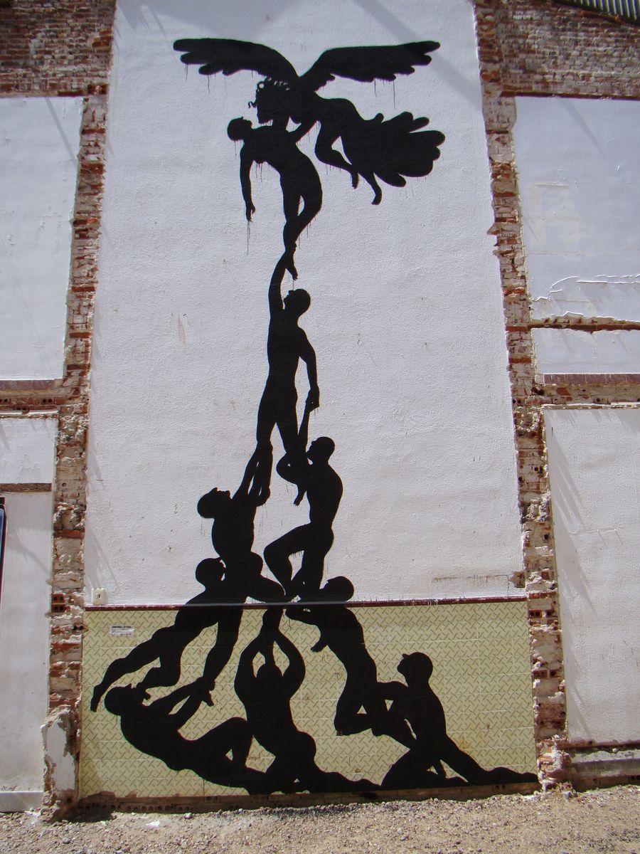 Close-up of black silhouette figures painted directly onto patterned ceramic tiles, overlapping torsos and arms in a tangled embrace, a faded poster fragment visible in the corner.