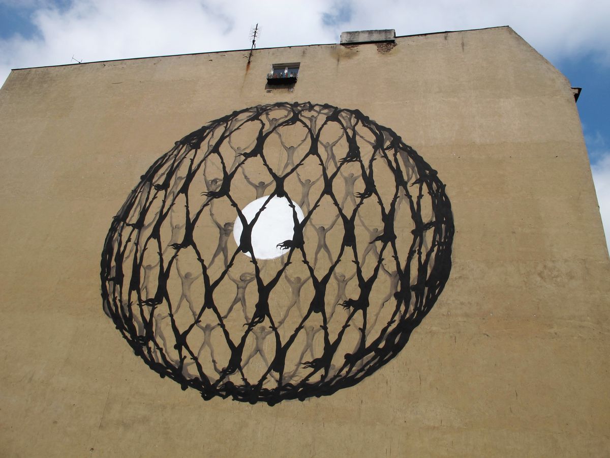Large gable wall painted with a black spherical net made of interlocking human figures holding hands, forming a globe shape with a white moon-like circle at its center, a small window near the roofline.