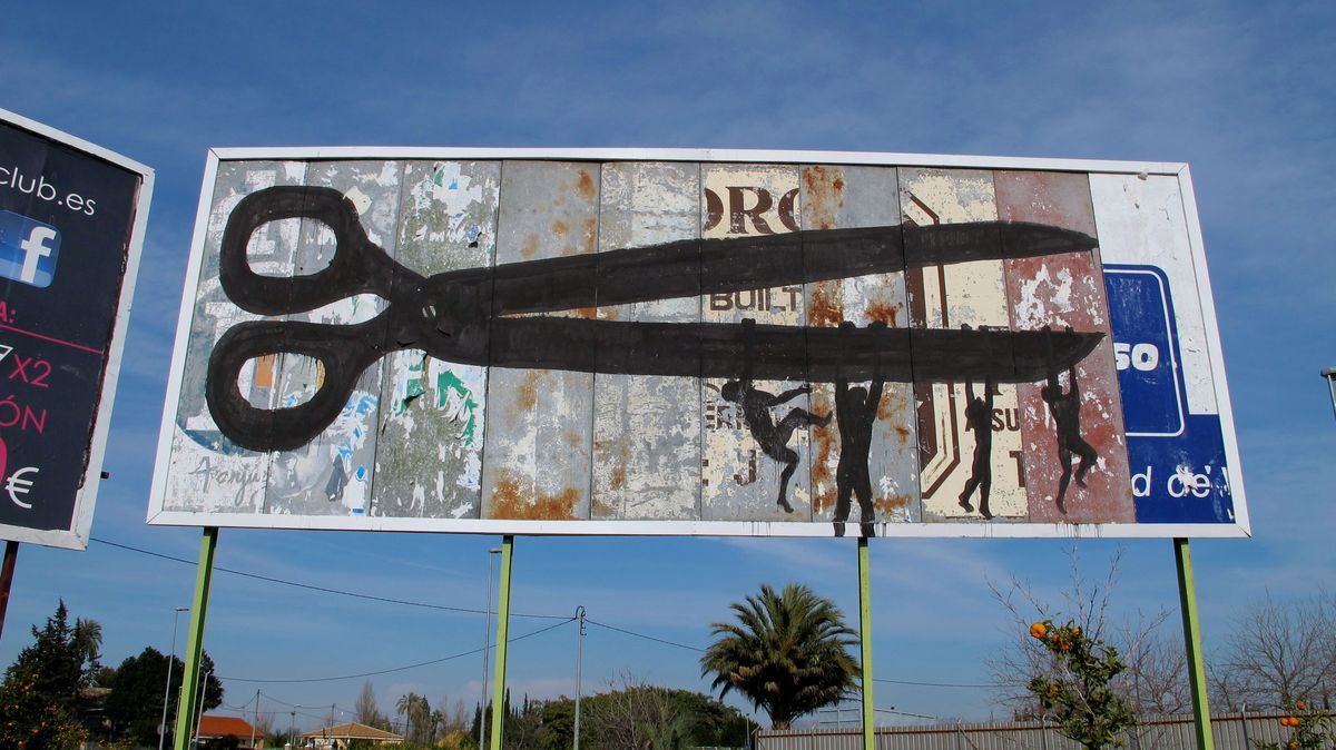 Large roadside billboard covered in rusted metal advertising panels, painted with giant black scissors, four small silhouette figures dangling and climbing from the lower blade, a palm tree and orange grove below.