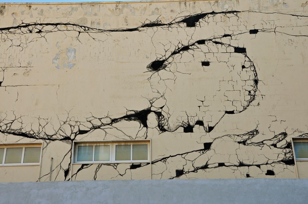 Close-up section of the crack mural showing dense branching black lines converging into a spiral shape above a row of windows.