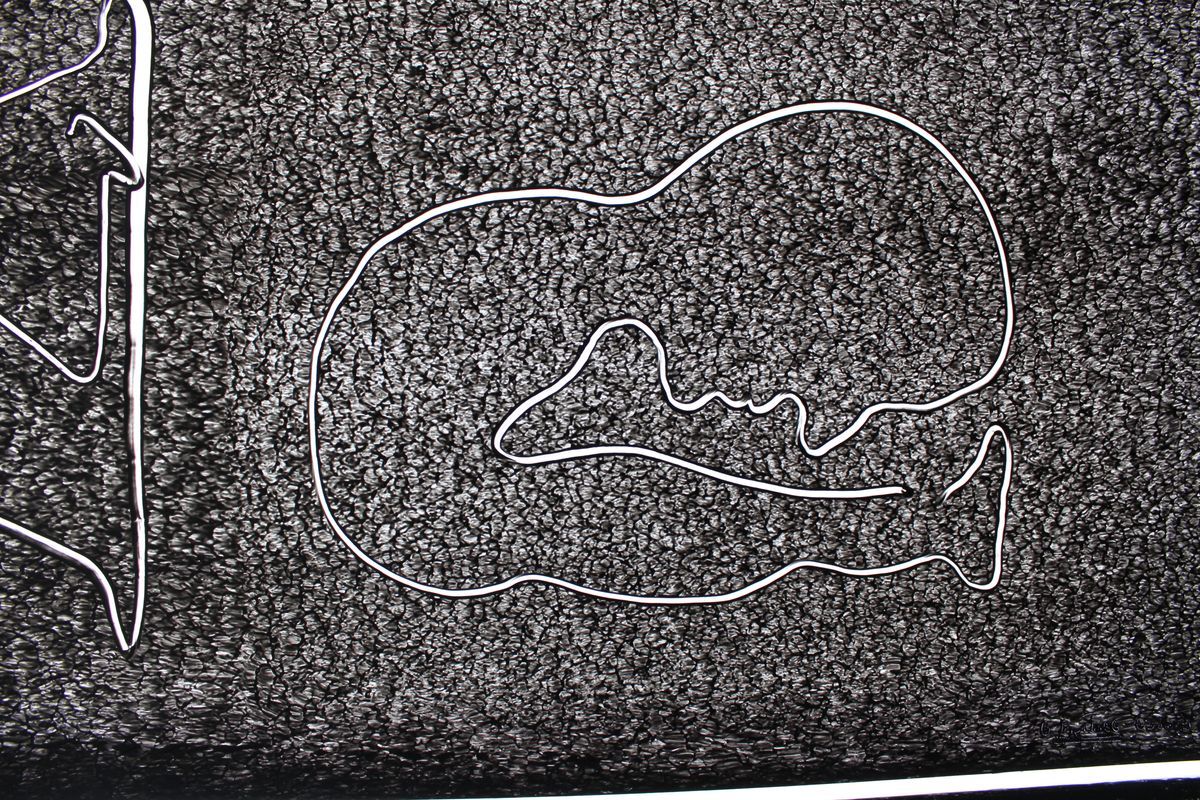 Close-up of a black ink drawing on paper showing a simplified skull-like outline next to a vertical abstract line shape.