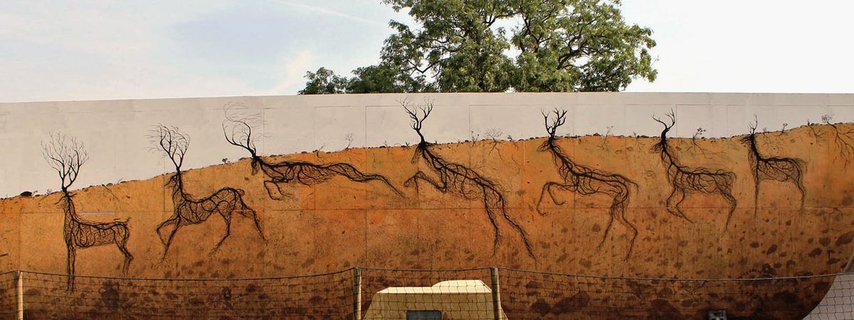 Four black wireframe deer made of tangled root lines, walking across a wall split between white sky above and ochre earth below, a green tree visible above the wall.