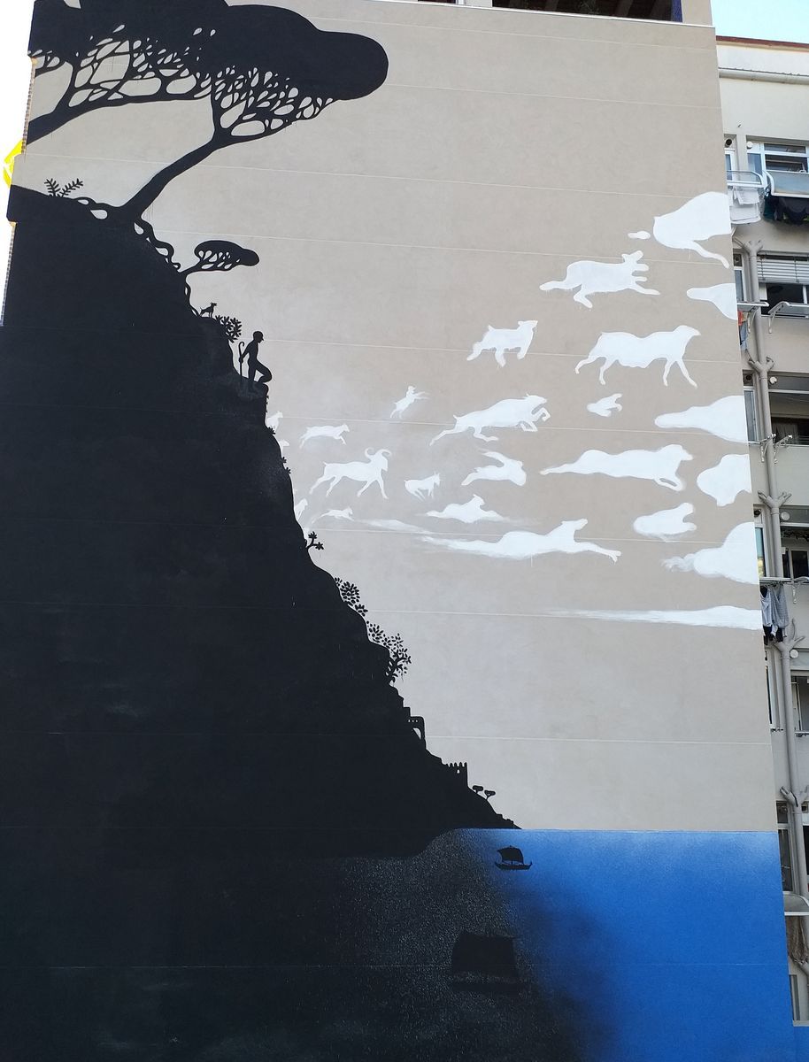 Close view of a building facade mural showing a black silhouette cliff with a tree and a shepherd figure, a flock of white cloud-shaped animals leaping across the tan sky toward the edge of the wall.