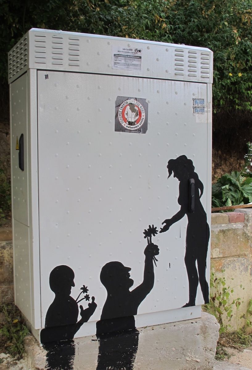 Black silhouette mural on the side of a utility box showing a standing woman handing a flower down to two smaller kneeling figures, each already holding flowers of their own.