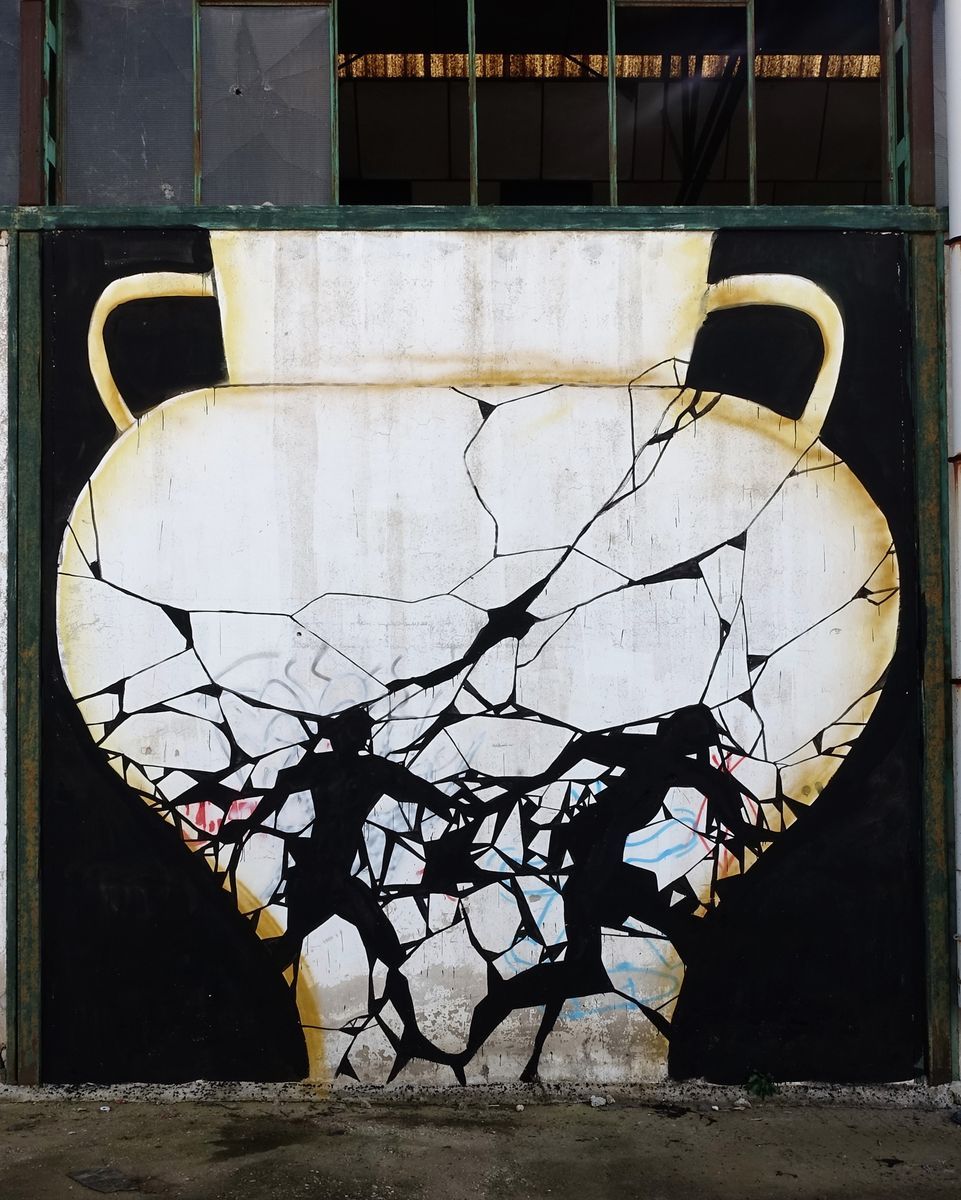 Mural of a large cracked amphora vase with two handles, painted in gold and white, two black silhouetted running figures breaking through the fractured lower half.