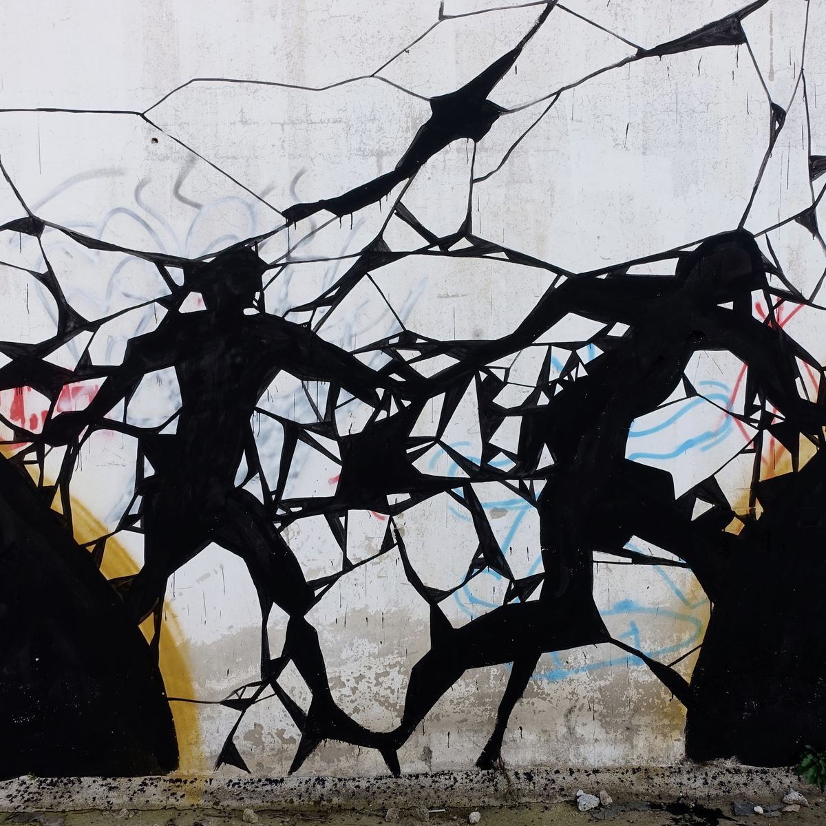 Detail of the amphora mural showing two black silhouetted figures breaking through a web of fractured lines on a weathered white wall, faint colored graffiti scribbles beneath.