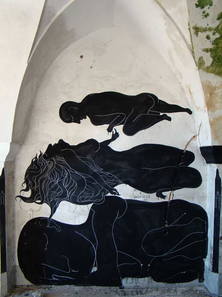 Black silhouette mural inside a vaulted stone niche showing a reclining nude woman with flowing hair rendered in white outline, a smaller curled figure floating above her, painted on a whitewashed arched wall.